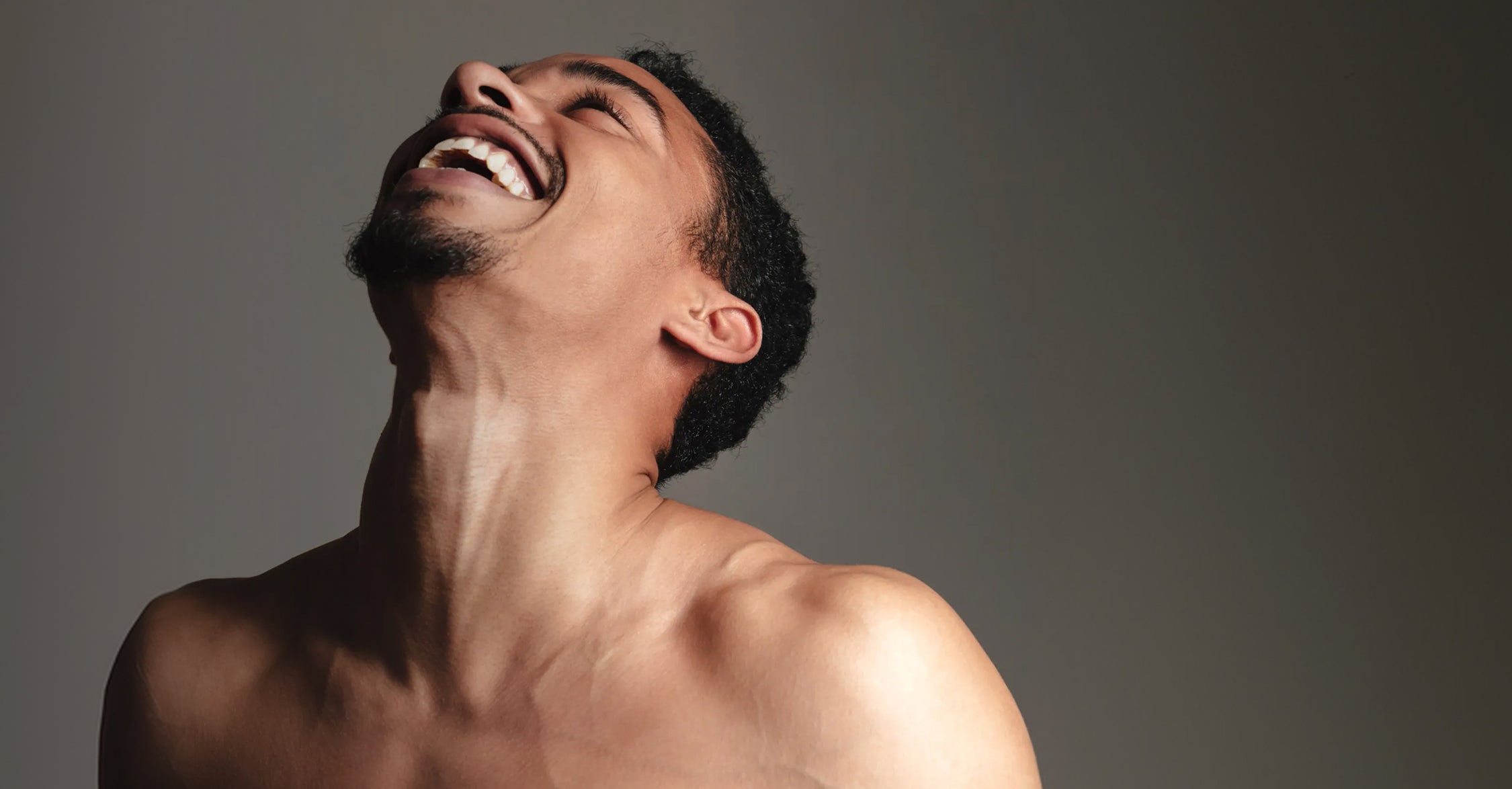 Shirtless man leaning his head back with a broad smile