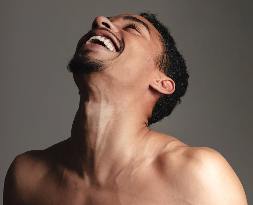 Shirtless man leaning his head back with a broad smile